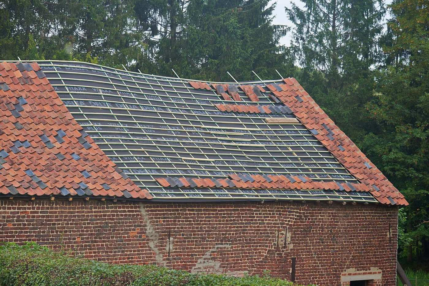 Hellend dak tijdens een herstelling, met panlatten en een deel van de pannen weggenomen